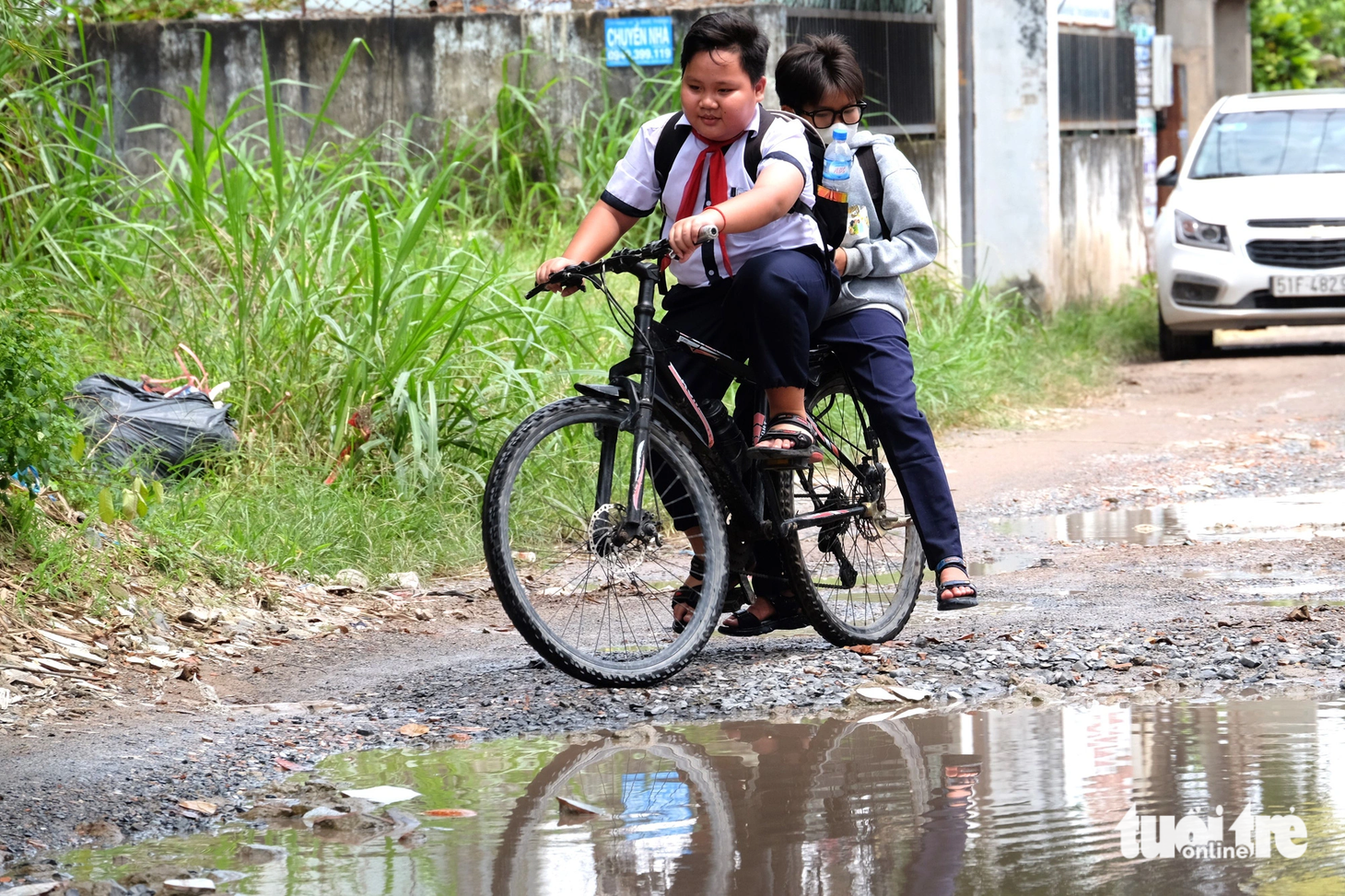 Hai học sinh loạng choạng né "ổ gà" trên đường Giác Đạo (xã Trung Chánh, huyện Hóc Môn) - Ảnh: PHƯƠNG NHI