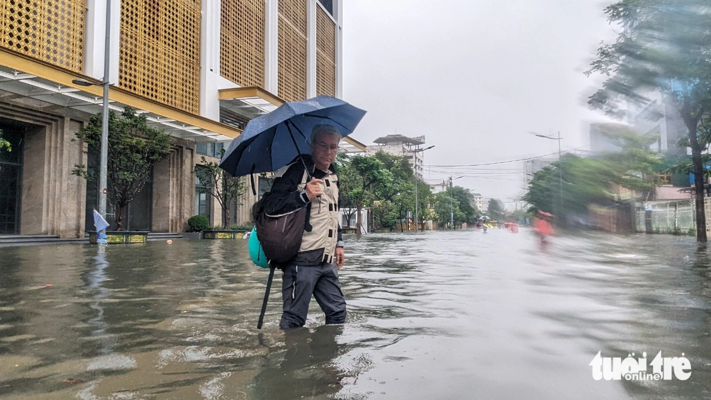 Một du khách nước ngoài lội nước lụt trên đường