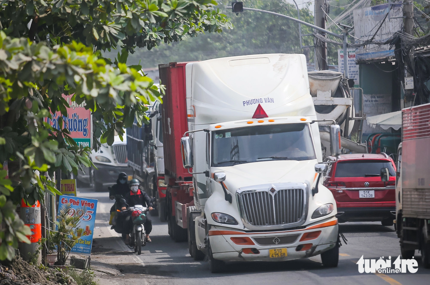 Xe máy, xe đạp chỉ còn khoảng nửa mét đường sát vỉa hè để đi. Chạy sát bên những "gã khổng lồ", ai cũng nơm nớp, tai nạn có thể xảy ra bất cứ lúc nào - Ảnh: LÊ PHAN