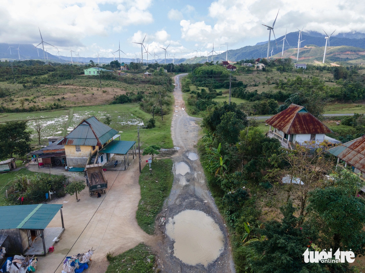 Nhiều hố nước sâu và rộng giữa đường, đằng sau là cánh đồng điện gió rộng lớn - Ảnh: HOÀNG TÁO