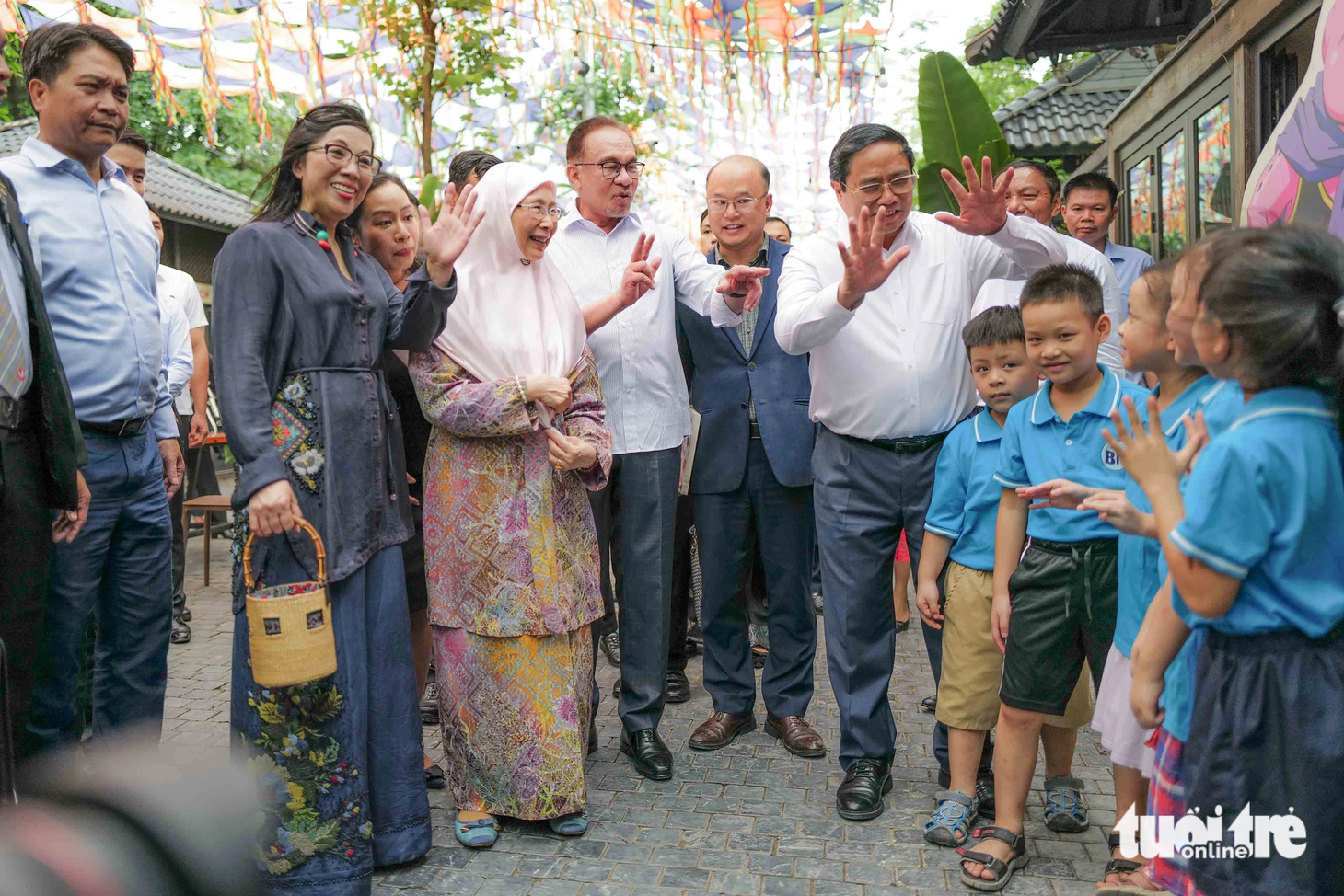Thủ tướng Phạm Minh Chính và Thủ tướng Malaysia Anwar Ibrahim cùng hai phu nhân trò chuyện với các em nhỏ tại đường sách - Ảnh: NGUYỄN KHÁNH