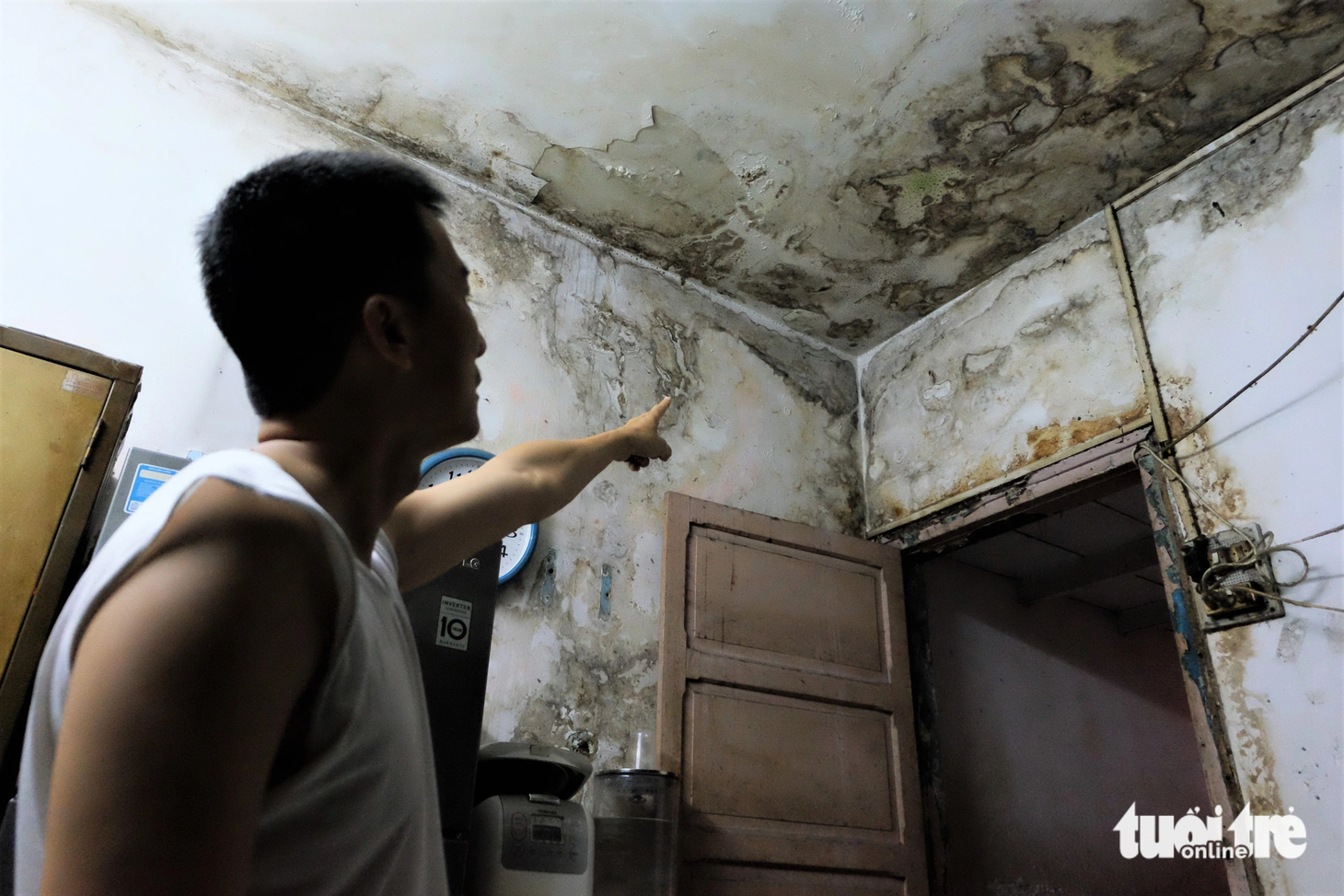Ông Nam, người dân sống tại đây, chỉ về khu vực thấm nước của căn phòng, lại là nơi gắn các thiết bị điện với nguy hiểm luôn chực chờ cả nhà - Ảnh: PHƯƠNG NHI