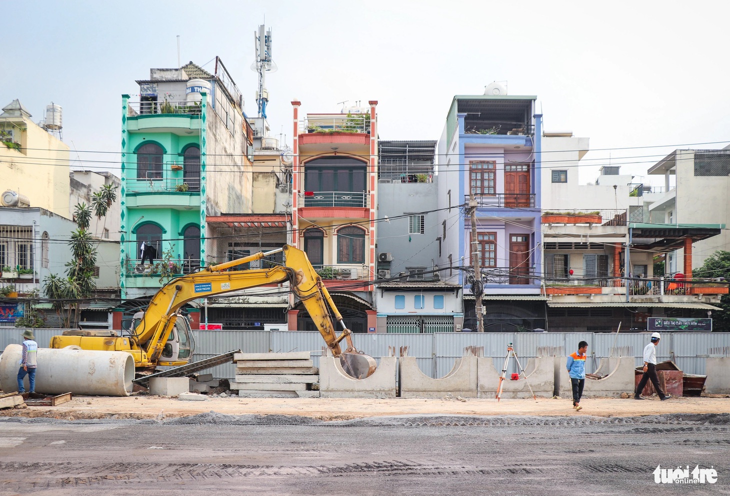 Các công nhân, kỹ sư và máy móc đang hoạt động tấp nập bên trong rào chắn công trường xây dựng đường nối Trần Quốc Hoàn với khu dân cư