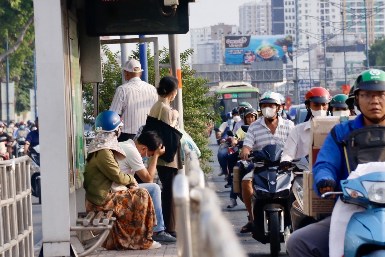 Một người đàn ông cúi gục mỏi mòn chờ xe buýt thoát khỏi kẹt xe qua đón trên đường Trường Chinh - Ảnh: TIẾN QUỐC