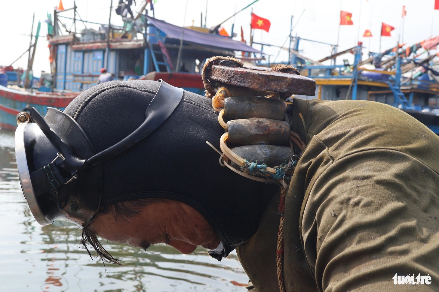 Ông Quyết phải mang thêm nhiều vòng chì trên người để có sức nặng dễ lặn xuống nước - Ảnh: LÊ TRUNG