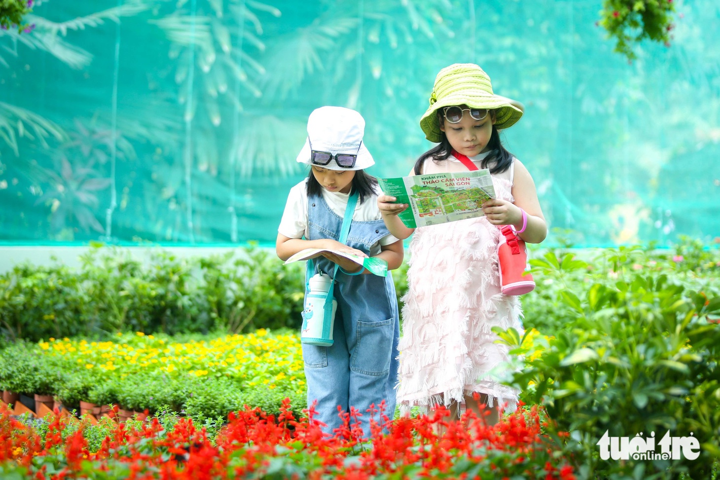 Mộc Trà (trái) cùng chị gái tìm hiểu thông tin về các loài bướm trên tờ giấy hướng dẫn - Ảnh: PHƯƠNG QUYÊN