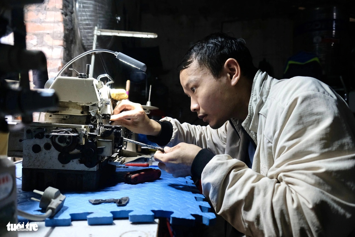 Vừa nghỉ việc ở công ty được khoảng hai tháng thì Quang phát hiện mắc bệnh ung thư hạch. Trong ảnh: Quang sửa chữa máy khâu tại nhà cho khách - Ảnh: NGUYÊN BẢO