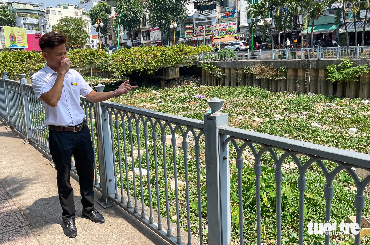 Chỉ tay về hướng rác đang ứ đọng, anh Mai Thành Liêm nói với phóng viên: "Cả tháng rồi mà kênh này không được dọn nên bốc mùi kinh khủng. Tôi mong đơn vị môi trường sớm thu gom sạch sẽ để cuộc sống người dân không bị ảnh hưởng" - Ảnh: CHÂU TUẤN