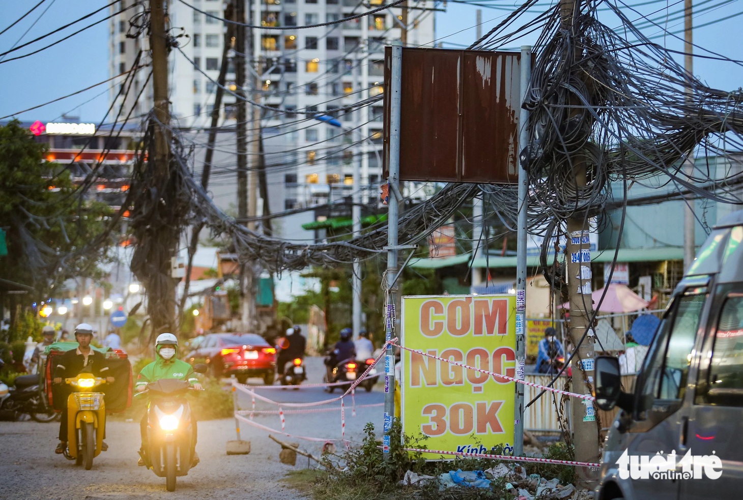 Sát nút giao Trần Não, 2 hàng cột điện với chi chít dây vẫn đứng giữa đường, để lại dấu hỏi với người dân về trách nhiệm phối hợp của điện lực - Ảnh: CHÂU TUẤN