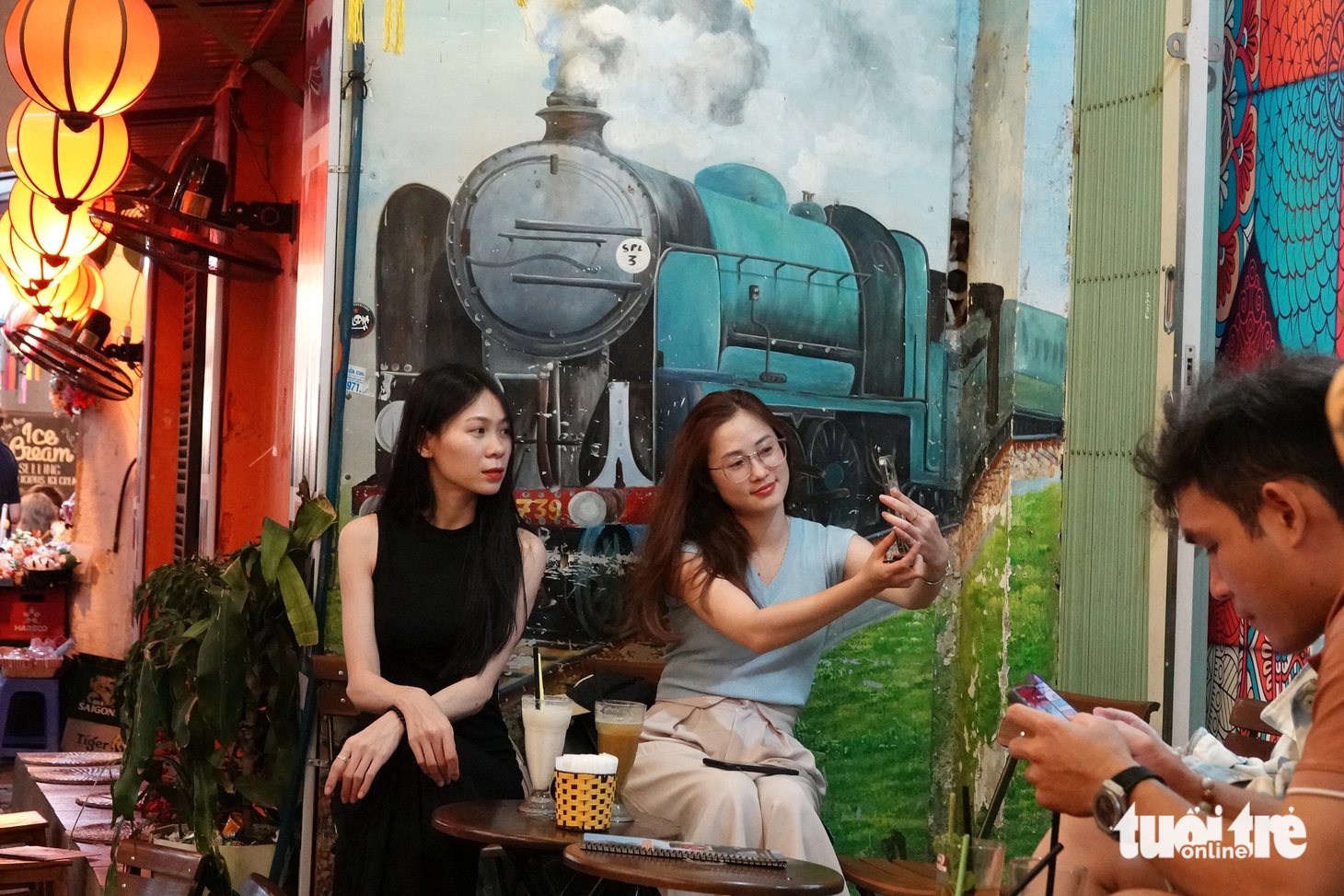 Hai du khách không đợi được tàu thì selfie với đoàn tàu trên bức tranh tường - Ảnh: T.T.D.