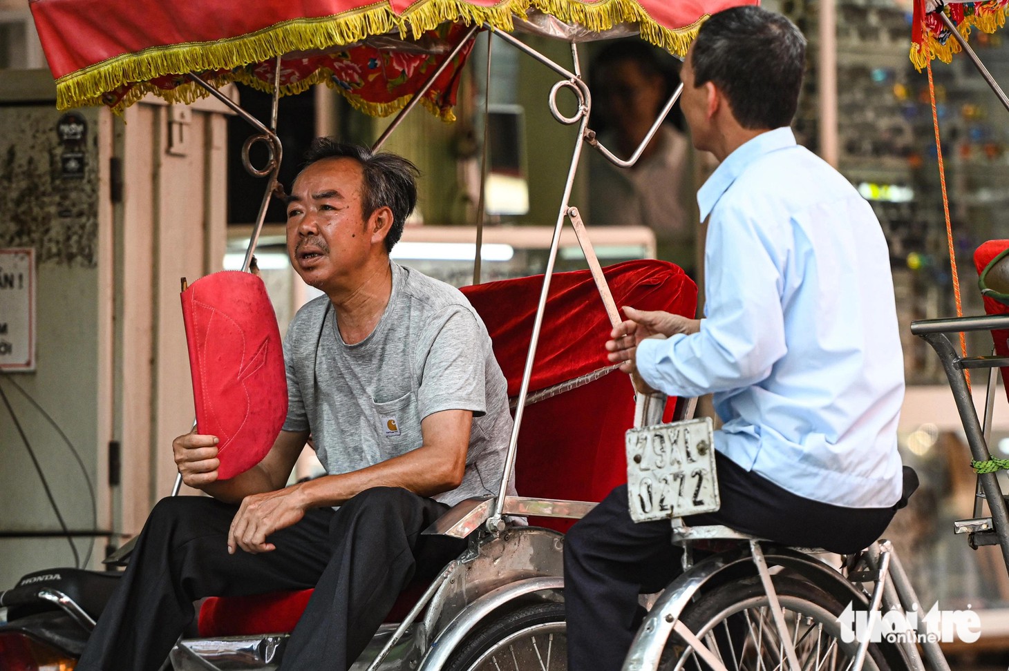 Bóng râm trở thành nơi trú chân của 2 người đàn ông đạp xích lô trên bờ hồ - Ảnh: HỒNG QUANG