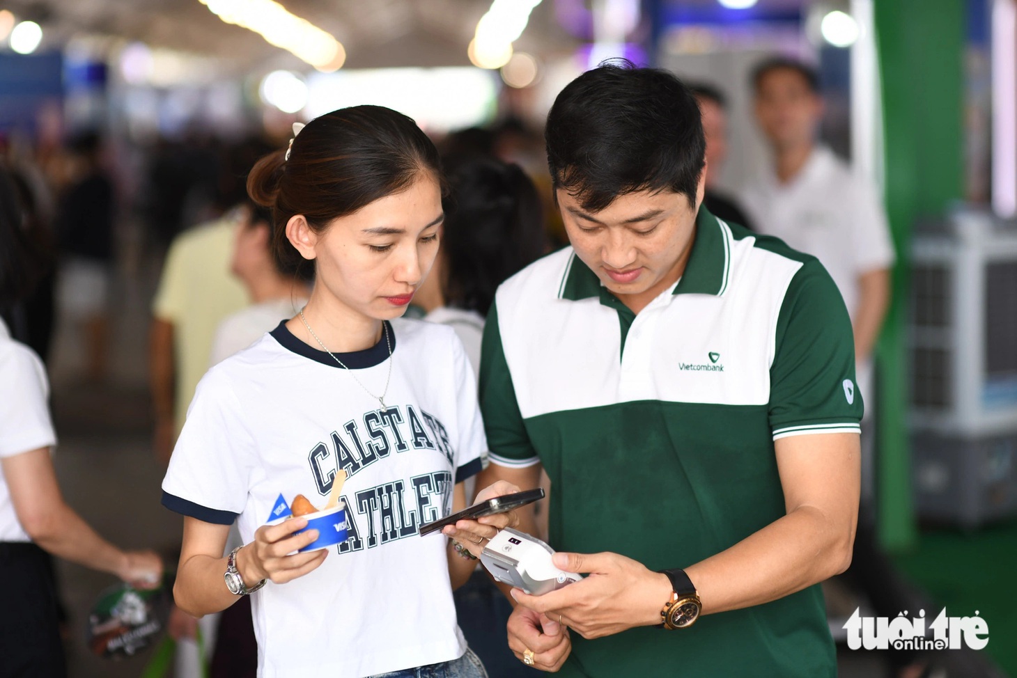 Nhân viên Vietcombank hướng dẫn người dân thanh toán một chạm để nhận ly cà phê miễn phí - Ảnh: QUANG ĐỊNH