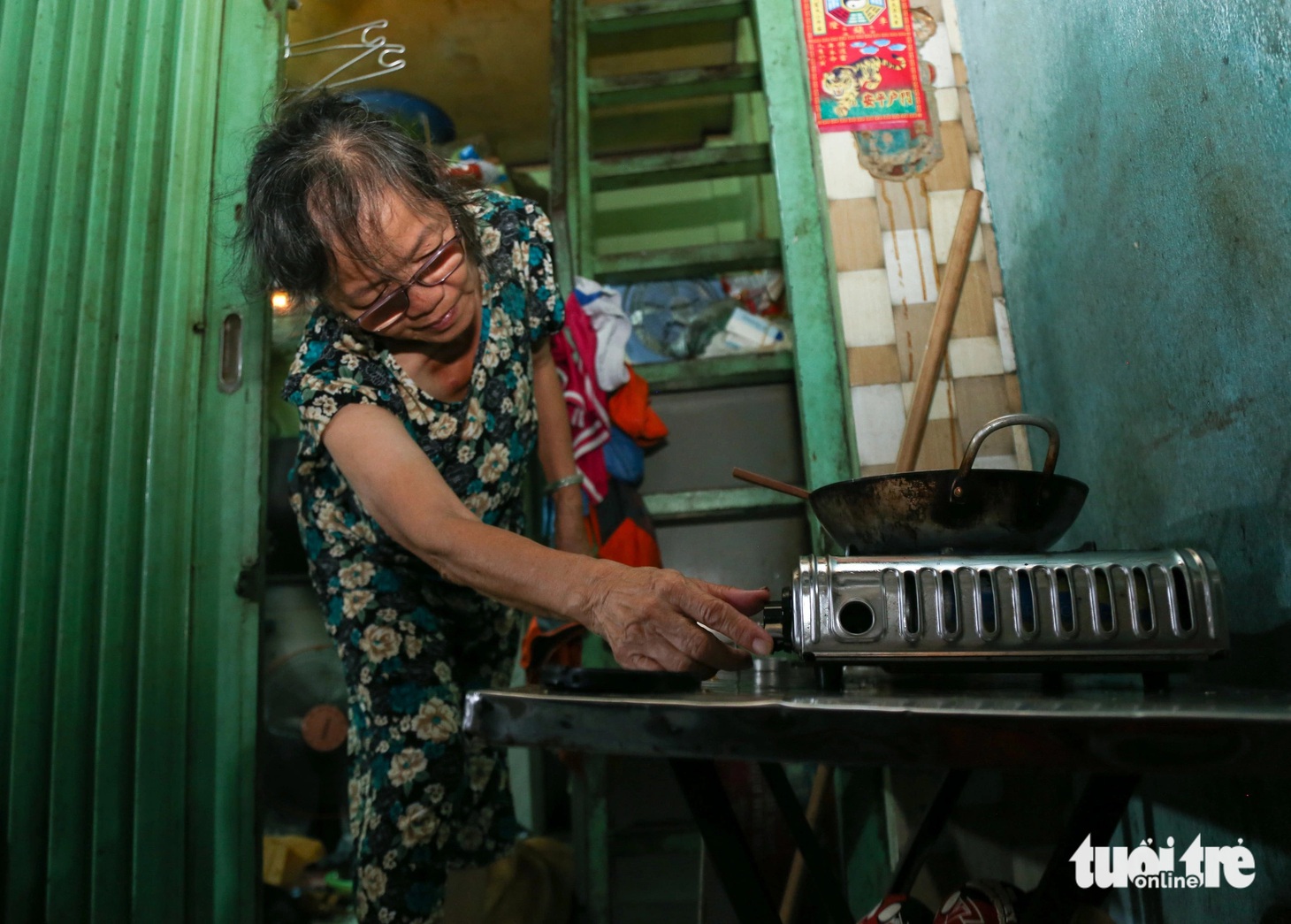 Người thì đông hơn nhưng căn nhà lại chẳng rộng ra, vẫn vỏn vẹn 4m2 cho 5, 6 người ở. Sau đó, chồng bà Hoa mất và cô con dâu qua đời vì ung thư. Căn nhà hiện còn 4 người ở, bà ở tầng dưới, con trai và hai cháu ở trên gác gỗ. Tất cả mọi sinh hoạt của gia đình diễn ra trước cửa nhà. Nấu ăn ngoài đường, ăn uống ngoài đường, giặt giũ ngoài đường rồi xe cũng để ngoài đường. Chiếc bếp gas nhỏ kê tạm ngoài trời để nấu cơm. Những ngày Sài Gòn mưa tầm tã, bếp gas bị "vô hiệu hóa", gia đình bà Hoa chỉ có thể ăn cơm trắng với chao - Ảnh: THẢO LÊ