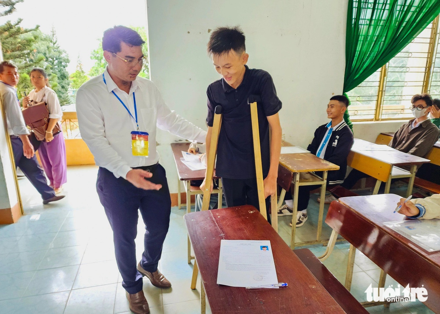 Thí sinh Thân Tiến Thịnh, dự thi tại điểm thi Trường THPT Trần Hưng Đạo (huyện Đắk Mil), được ông Phan Thanh Hải - giám đốc Sở Giáo dục và Đào tạo tỉnh Đắk Nông dìu vào bàn thi - Ảnh: TÂM AN