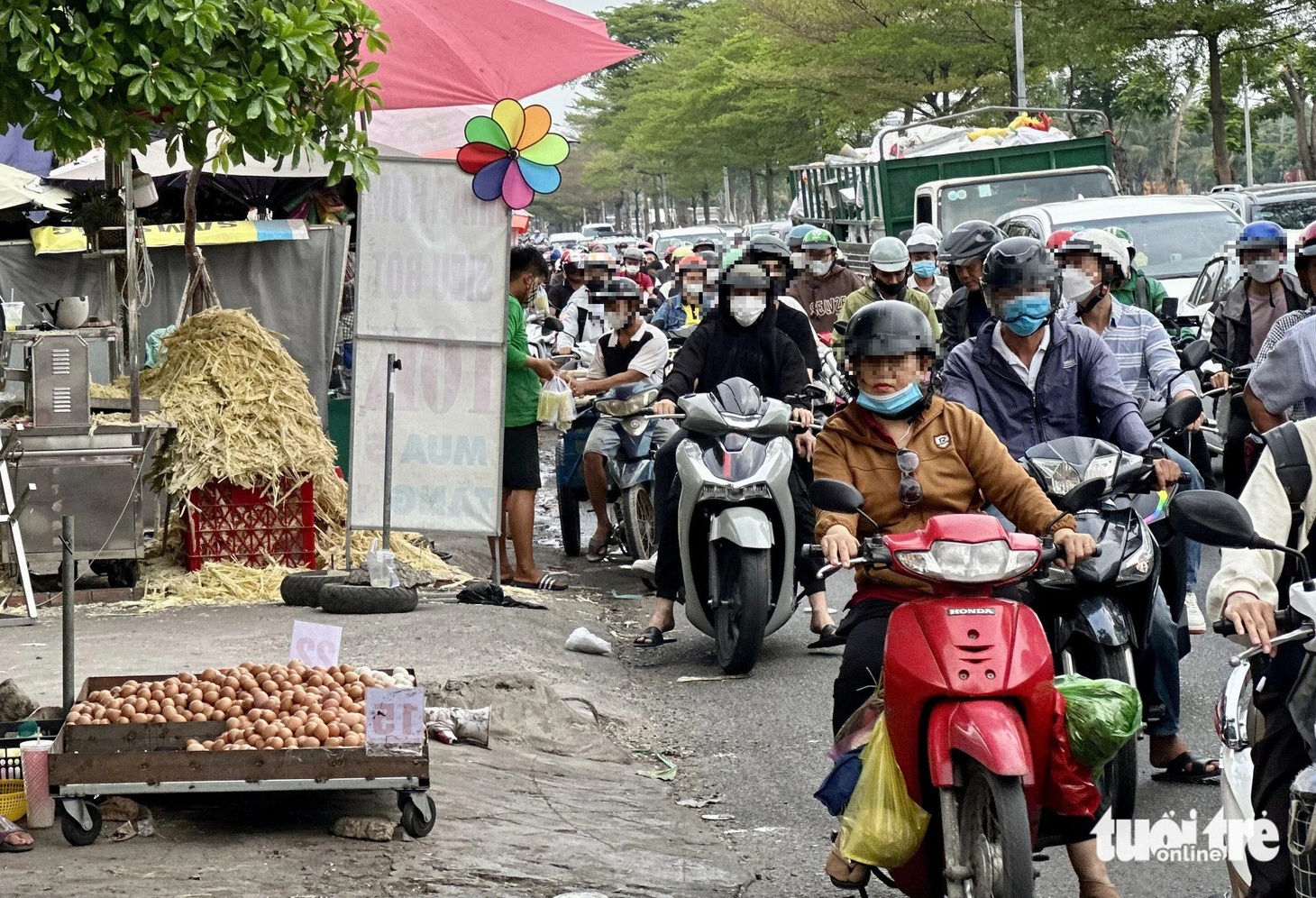 Nhiều người thản nhiên đứng dưới lòng đường mua hàng mặc kệ dòng xe chen chúc phía sau - Ảnh: NGỌC QUÝ