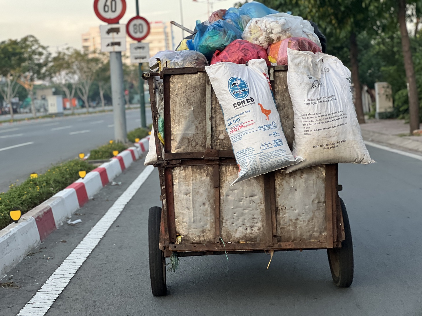 Một chiếc xe rác đã xuống cấp chở đầy ắp chạy bon bon trên đường Phạm Văn Đồng, Thủ Đức