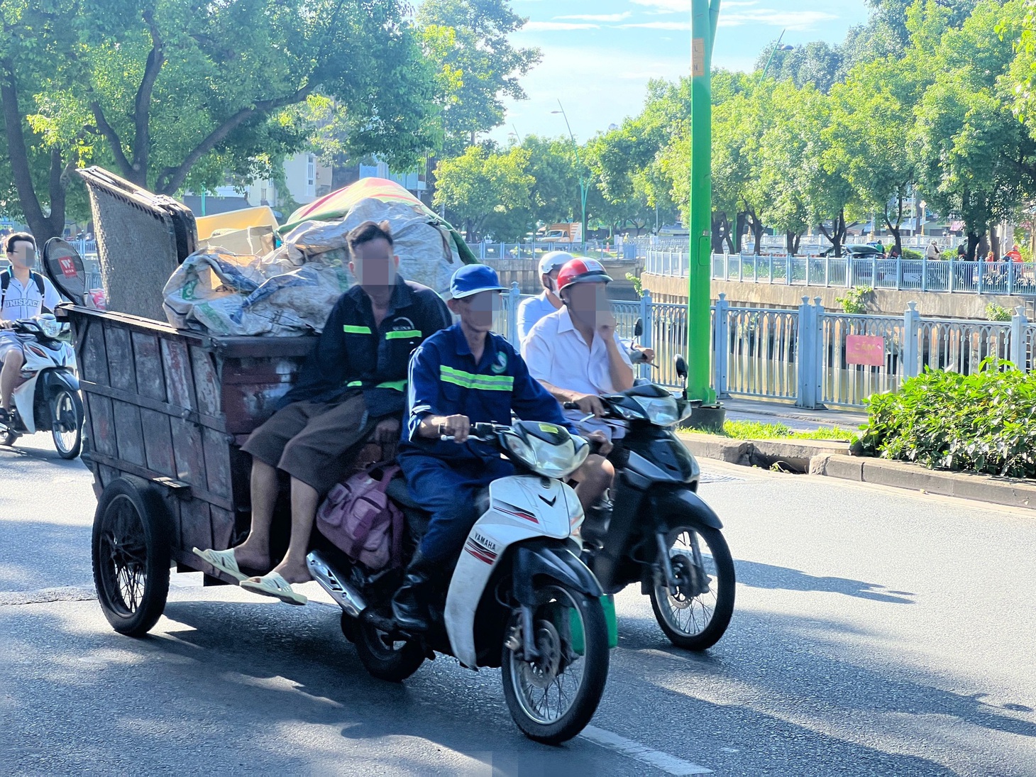 Những người ngồi trên xe rác không ai đội mũ bảo hiểm