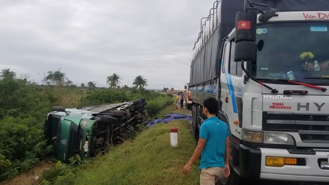 Hai xe tải lao xuống ruộng khi di chuyển trong bão nghi do mất lái - Ảnh 1.