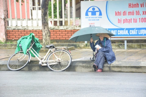 Những người già bán vé số đội mưa, co ro trong giá rét để mưu sinh - Ảnh 1. Những người già bán vé số đội mưa, co ro trong giá rét để mưu sinh - Ảnh 1.