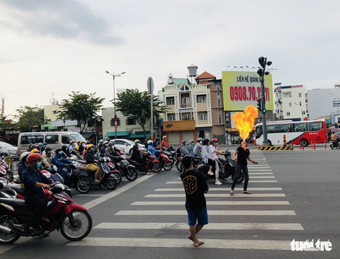 Người biểu diễn ngậm dầu phun lửa tràn ra các ngã tư đường, nguy cơ mất an toàn - Ảnh 1. Người biểu diễn ngậm dầu phun lửa tràn ra các ngã tư đường, nguy cơ mất an toàn - Ảnh 1.