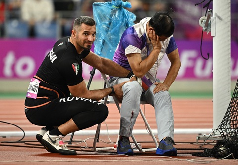 VĐV ném búa Ali Zankawi sơ cứu bước đầu cho trọng tài Huang Qinhua - Ảnh: REUTERS VĐV ném búa Ali Zankawi (áo đen) sơ cứu bước đầu cho trọng tài Huang Qinhua - Ảnh: REUTERS