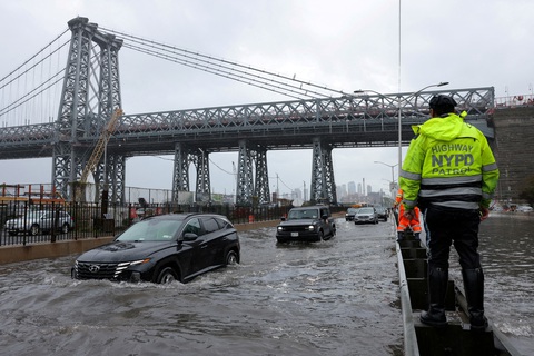 Cảnh sát New York quan sát ô tô đi qua con đường ngập nước, ngày 29-9 - Ảnh: REUTERS Cảnh sát New York quan sát ô tô đi qua con đường ngập nước, ngày 29-9 - Ảnh: REUTERS