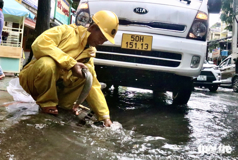Mới mưa 30 phút đường đã ngập mênh mông, cá bơi lên đường - Ảnh 9. Mưa lớn, nhân viên thoát nước bắt được cá bơi trên đường Lê Văn Thọ (quận Gò Vấp)