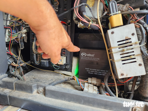 CSGT xử phạt xe khách trả khách không đúng quy định trên quốc lộ 1 - Ảnh 1. Lực lượng chức năng yêu cầu tài xế mở vị trí lắp đặt "hộp đen" để kiểm tra - Ảnh: MINH HÒA