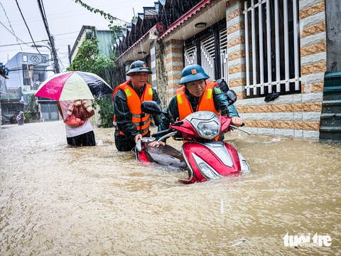 Chính quyền, bộ đội mang xuồng hộ tống dân đi tránh lụt - Ảnh 7. Dân quân giúp dân di dời xe máy ra khỏi vùng ngập lụt sâu tại phường Hòa Khánh Nam - Ảnh: TẤN LỰC
