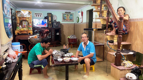 Mưa giảm, nhiều vùng thấp trũng ở Huế vẫn ngập sâu trong nước lũ - Ảnh 2. Bữa cơm trưa vội vã của gia đình ông Nguyễn Khôi (xã Lộc Trì, huyện Phú Lộc) trong nước lũ - Ảnh: BẢO PHÚ