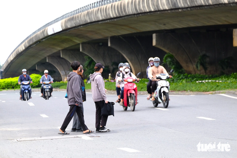 Thờ ơ với hầm đi bộ và cầu vượt, dân liều lĩnh băng ngang đường - Ảnh 4. Ngược lại, bên trên hầm chui, dòng người băng ngang sang đường tấp nập. Hầu hết người dân băng ngang qua quốc lộ 1 đông nghẹt xe tải, mặc kệ dòng xe tải bấm còi inh ỏi. Trong khi đó, khu vực giao lộ này là một trong những điểm đen liên tục xảy ra tai nạn giao thông. Giờ tan tầm, nhiều công nhân đi thành đoàn, giơ tay xin đường.