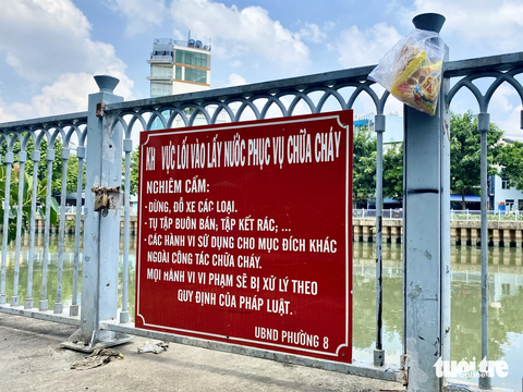 Những hình ảnh xấu xí dọc kênh Nhiêu Lộc - Thị Nghè - Ảnh 7. Bên cạnh biển báo cấm là một bọc rác treo lủng lẳng - Ảnh: TIẾN QUỐC