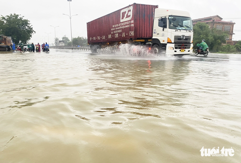Nước lũ tràn lênh láng trên quốc lộ 1 qua Quảng Nam, xe cộ ì ạch qua lại - Ảnh 4. Nước tràn lên mặt đường, ngập sâu khoảng 20cm - Ảnh: LÊ TRUNG