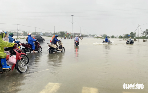 Nước lũ tràn lênh láng trên quốc lộ 1 qua Quảng Nam, xe cộ ì ạch qua lại - Ảnh 7. Công nhân Khu công nghiệp Tam Thăng dắt xe qua đoạn ngập - Ảnh: LÊ TRUNG