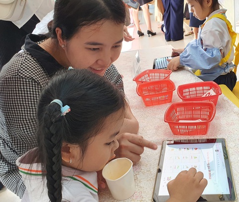 TP.HCM: Học sinh mầm non thích thú sắm vai nhân viên siêu thị - Ảnh 4. Học sinh mầm non và phụ huynh cùng chọn hàng ở máy tính bảng của siêu thị đồng giá