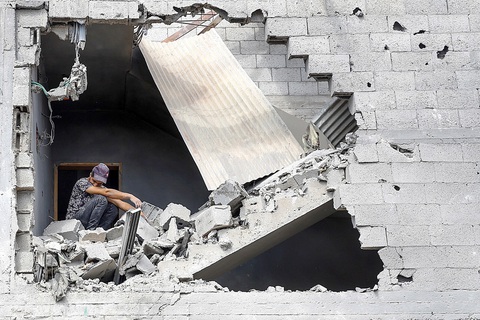 "Vết dầu loang" từ chiến sự Dải Gaza - Ảnh 1. Một người đàn ông ngồi trong ngôi nhà bị phá hủy do các cuộc tấn công trả đũa của Israel ở thành phố Khan Younis, phía nam Dải Gaza, vào ngày 16-10 - Ảnh: Reuters