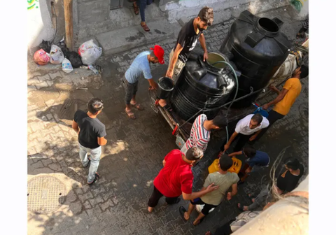 Người đàn ông và chú lừa kéo xe đi phân phát nước tại Dải Gaza - Ảnh 2. Người dân Palestine tại Dải Gaza phân phối nước - Ảnh: AL JAZEERA