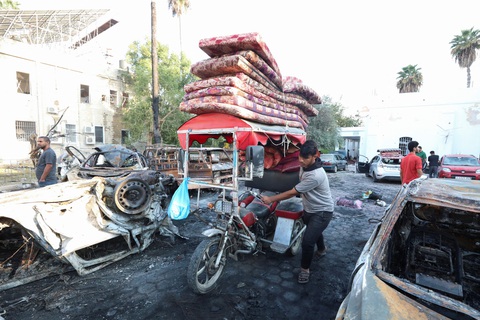 Thế giới đồng loạt lên án vụ tấn công bệnh viện khiến 500 người chết ở Gaza - Ảnh 1. Một người đàn ông mang những tấm nệm của mình đến Bệnh viện Al-Ahli Arabi để giúp đỡ các nạn nhân trong vụ tấn công tối 17-10 - Ảnh: REUTERS