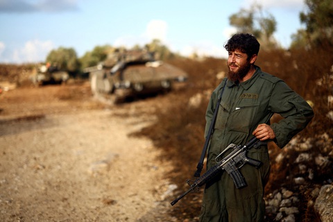 Israel sơ tán cả thành phố do xung đột với quân Hezbollah - Ảnh 1. Một người lính Israel bên cạnh chiếc xe tăng của quân đội Israel gần biên giới với Lebanon hôm 19-10 - Ảnh: REUTERS