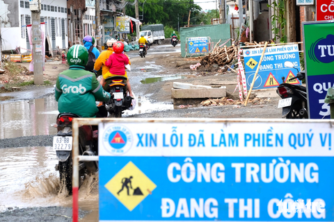 Cảnh học sinh sụp 'ổ gà' trên những tuyến đường 'nát' ở TP.HCM - Ảnh 9. Tuyến đường đang triển khai thực hiện dự án nâng cấp, mở rộng. Tuy nhiên, nhiều hộ dân chưa bàn giao mặt bằng nên dự án còn dang dở. Địa phương đang triển khai dự án theo kiểu cuốn chiếu, có mặt bằng tới đâu thi công tới đó. Nhiều người dân đi ngang các con đường này không muốn tấm bảng "xin lỗi" này tồn tại ngày này qua ngày khác - Ảnh: PHƯƠNG NHI