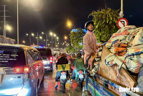 Hơn hai tiếng ‘chôn bánh xe’ ở quốc lộ 1, tài xế ‘sốt ruột’ tắt máy, đi bộ ngóng tình hình - Ảnh 6. Một tài xế xe lôi trèo lên yên xe để hóng tình hình ùn tắc phía sau - Ảnh: CHÂU TUẤN
