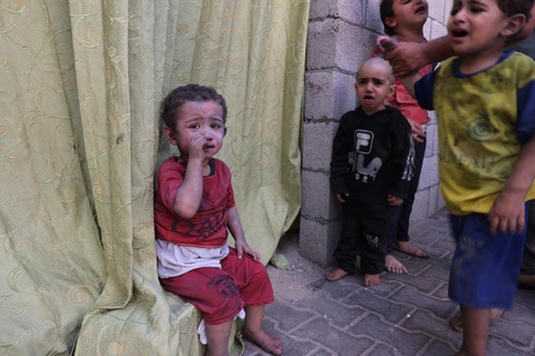 Hiện tượng mới ở Dải Gaza: Những dòng tên viết bằng mực đen trên bụng trẻ - Ảnh 1. Trẻ em Palestine, bị phủ đầy bụi từ các cuộc không kích của Israel, đang ngồi trong một khu đất thuộc Bệnh viện Rafah, phía nam Dải Gaza ngày 23-10 - Ảnh: AFP