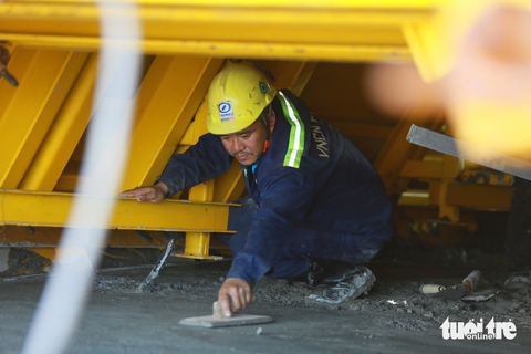 Cầu Bình Khánh tuyến cao tốc Bến Lức - Long Thành hồi sinh - Ảnh 2. Một công nhân làm phẳng bê tông trong hộc đúc. Sau khi tái khởi động, việc thi công diễn ra hối hả để tiến độ dự án được đáp ứng. Nhiều năm vắng bóng công nhân, nay công trường đã hồi sinh trở lại. Tiếng máy móc, phân công công việc rôm rả một góc sông Soài Rạp
