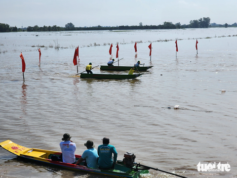 Hàng ngàn người ‘đội nắng’ xem đua xuồng trên cánh đồng lũ - Ảnh 1. Cặp đua xuồng tranh tài khi quay đầu về đích - Ảnh: BỬU ĐẤU