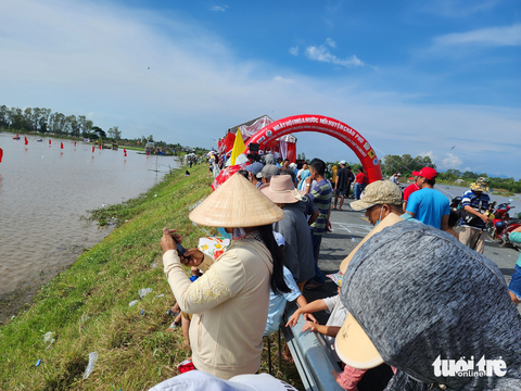 Hàng ngàn người ‘đội nắng’ xem đua xuồng trên cánh đồng lũ - Ảnh 5. Người dân đứng chật kín cả tuyến đường xem đua xuồng mùa lũ - Ảnh: BỬU ĐẤU