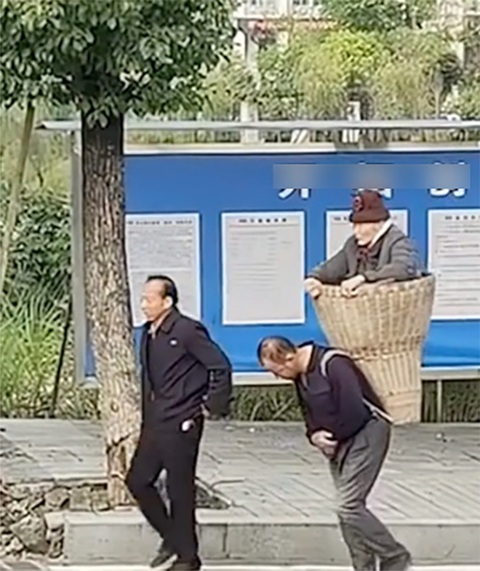 Hai anh em thay phiên gùi mẹ già 89 tuổi đến bệnh viện - Ảnh 1. Hình ảnh hai anh em gùi mẹ trên lưng gây xúc động