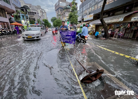 Bung nắp cống ‘giải cứu’ đường bị triều cường ngập ở trung tâm TP.HCM. - Ảnh 1. Nhân viên thoát nước đô thị phải bật tung nắp cống đường Calmette (quận 1, TP.HCM) để giảm ngập do triều cường - Ảnh: CHÂU TUẤN