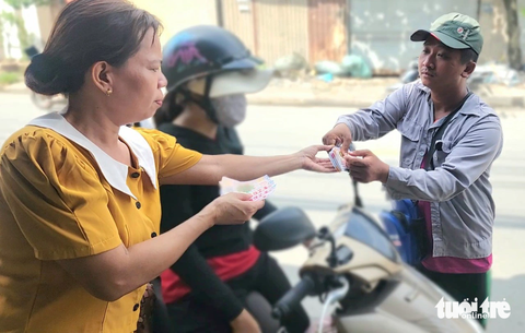 Người khuyết tật bán vé số dạo bị giật gần 200 vé, nhiều người xúm lại giúp đỡ - Ảnh 1. Một người trên đường Võ Văn Vân (xã Vĩnh Lộc B, huyện Bình Chánh) mua vé số của anh Lý Đăng Khoa vào ngày 29-10 - Ảnh: NGỌC KHẢI