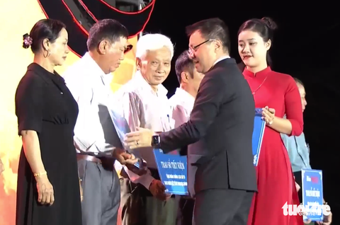 'Truông Bồn - Dấu chân Anh hùng' - Ảnh 3. Ông Lê Quốc Minh, tổng biên tập báo Nhân Dân, trao sổ tiết kiệm cho thân nhân liệt sĩ TNXP Truông Bồn - Ảnh: DOÃN HÒA