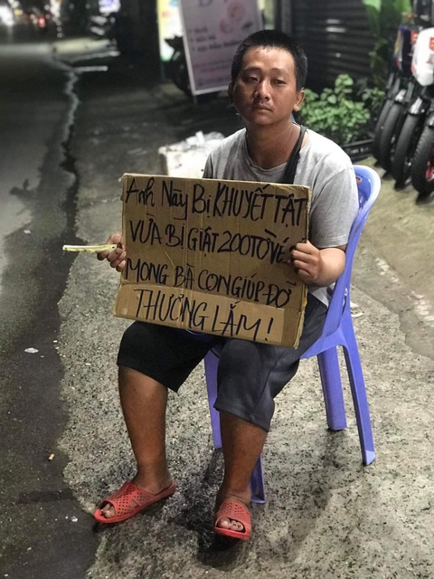Người bán vé số dạo bị kẻ gian giật vé số, người dân xúm lại giúp - Ảnh 3. Hình ảnh anh Khoa cầm tấm bảng ngồi bên đường do người dân chụp lại chia sẻ trên mạng xã hội